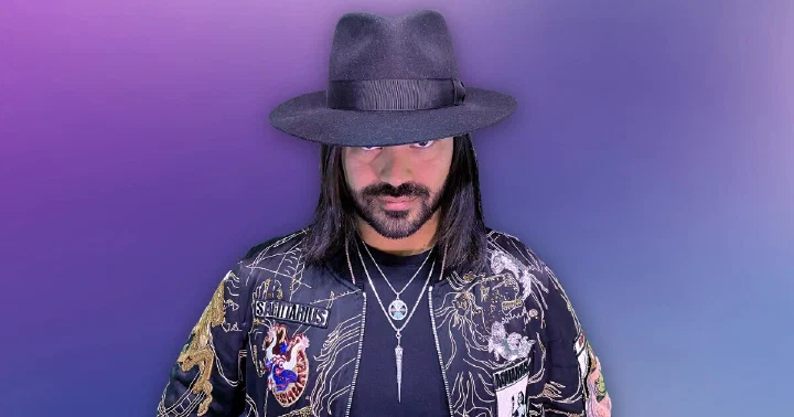Roshtein in his black fedora and embroidered jacket on a violet background